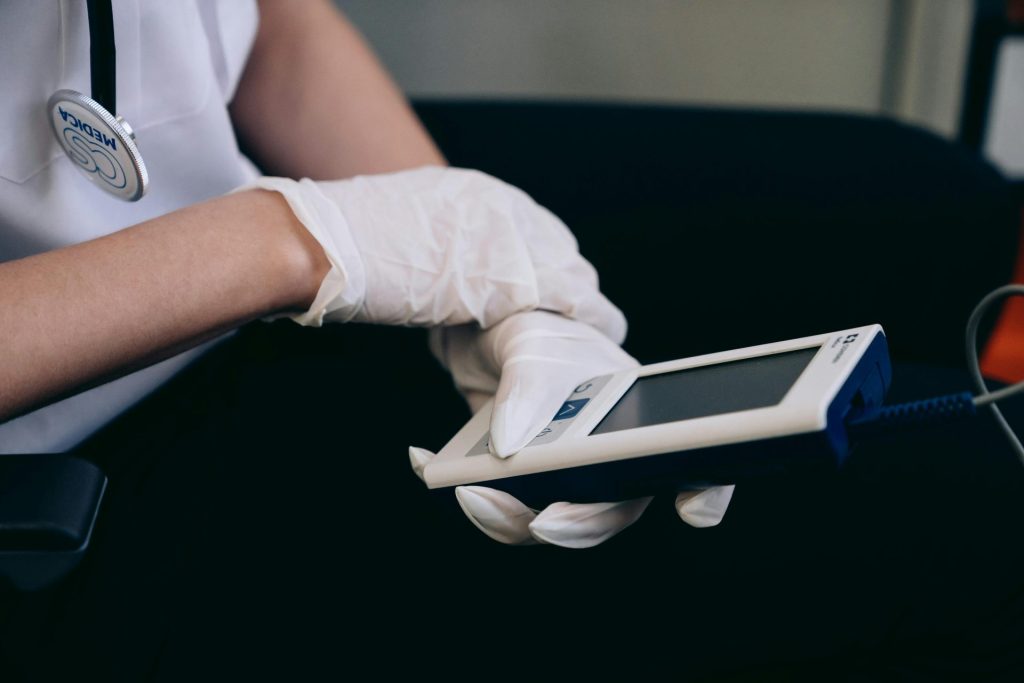 Mitarbeiter im Gesundheitswesen mit Handschuhen, die medizinische Geräte in Innenräumen verwenden.